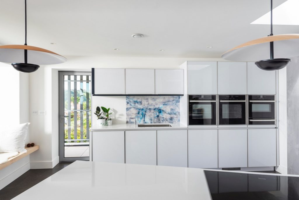 white kitchen with multiple cookers and bright personalised kitchen splashback.